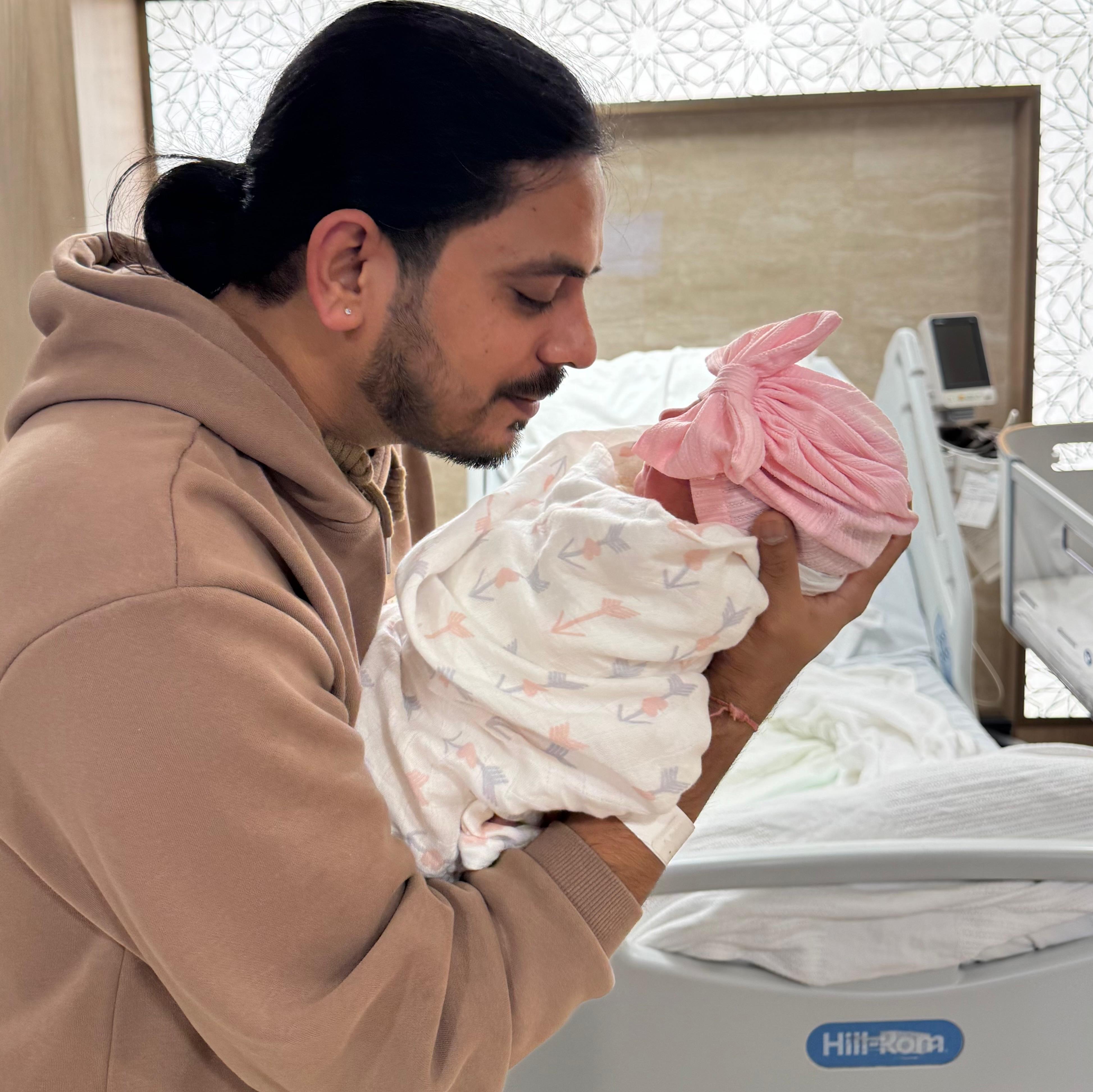A dad gently holding his newborn daughter for the first time in the hospital